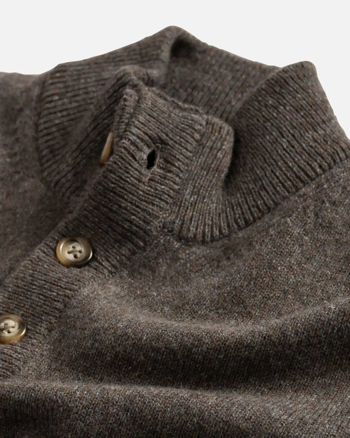 Closeup of the collar of a light brown mock neck Italian merino sweater.