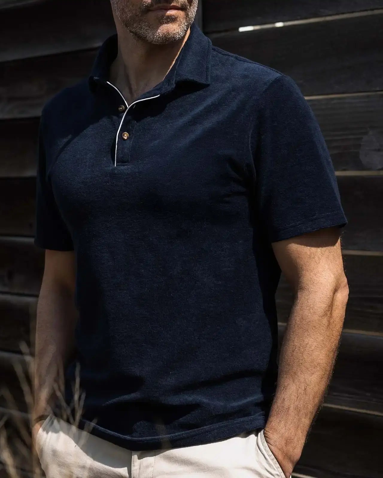 Man wearing a navy blue terry cloth polo shirt against a wooden background