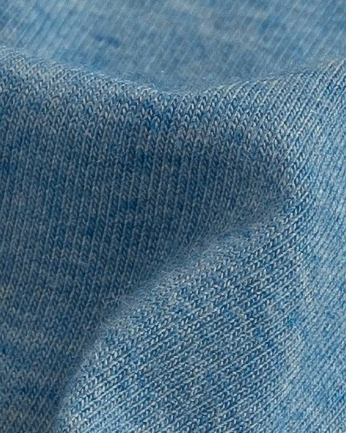 A close-up of light blue knit fabric with a fine ribbed texture and soft folds.