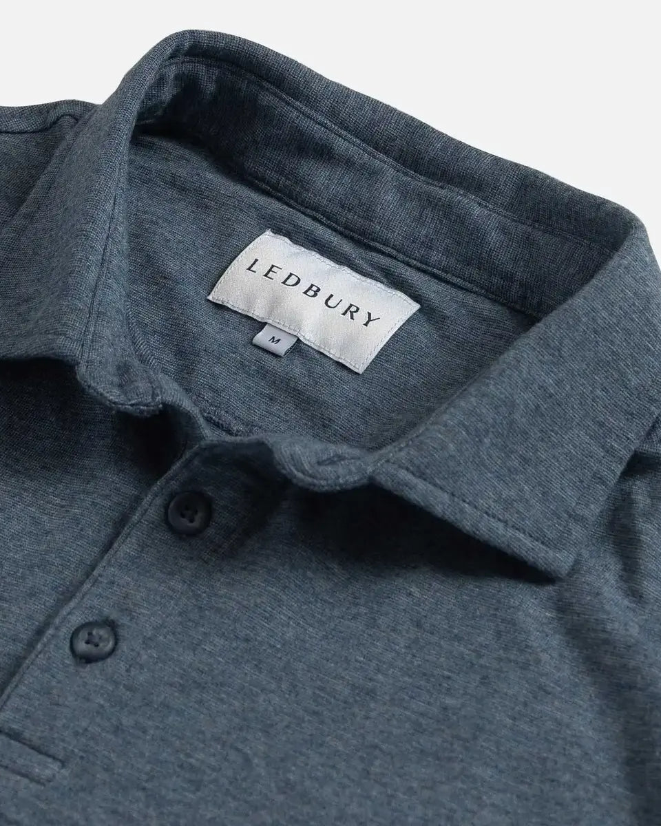 Close-up of a slate blue polo shirt collar with a visible LEDBURY neck label and two dark buttons on a light gray background.