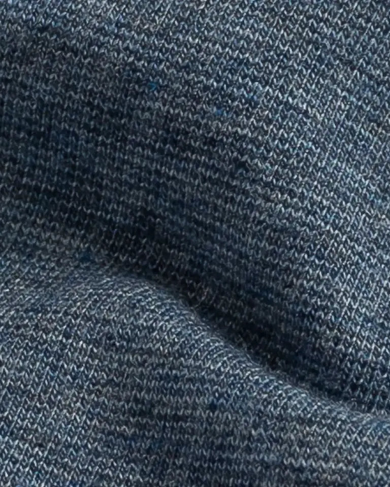 A close-up of a heathered blue knit fabric texture with a fine ribbed pattern and soft folds.