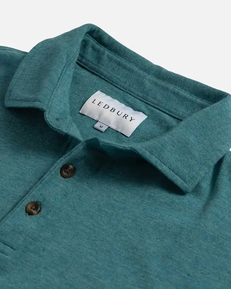 Close-up of a teal heathered polo shirt collar with brown buttons and a visible LEDBURY neck label on a light gray background.