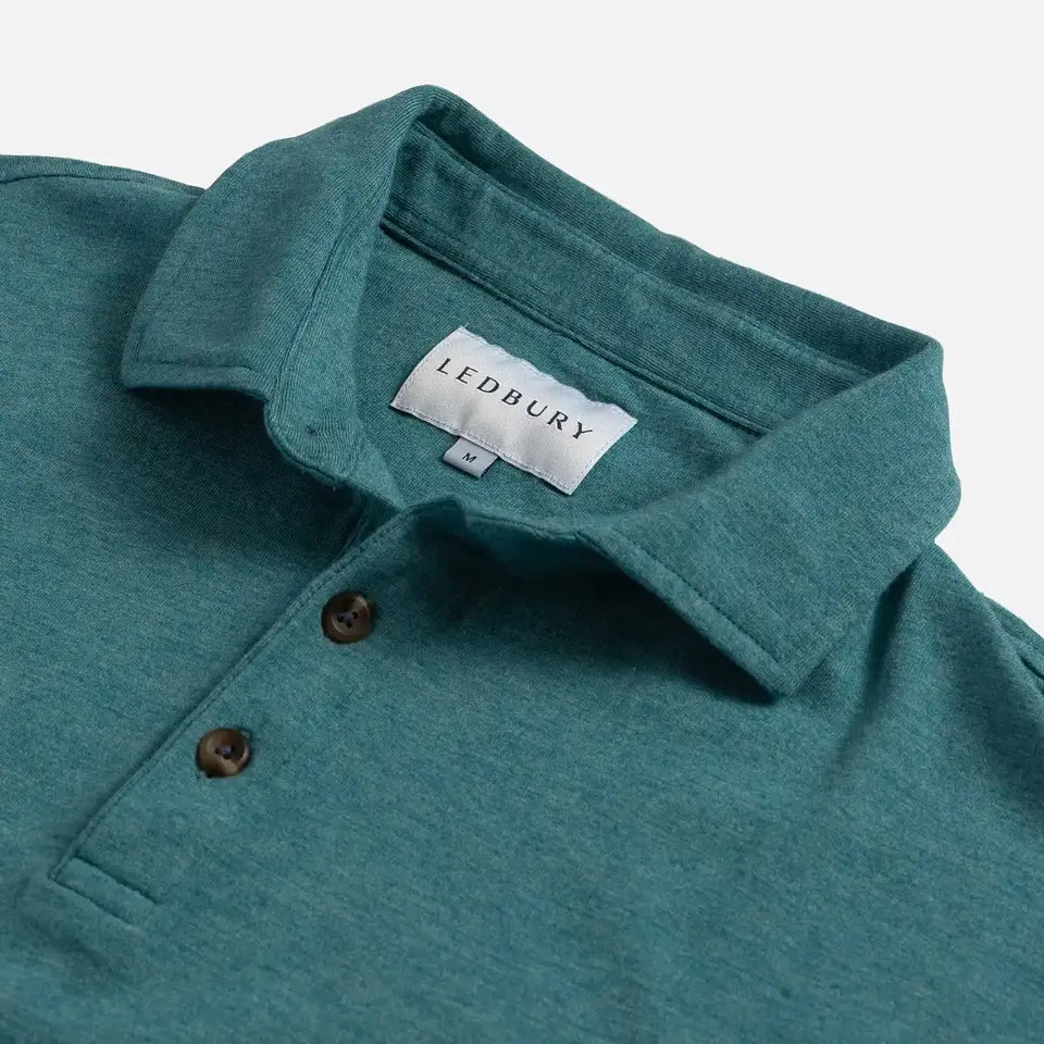 Close-up of a teal heathered polo shirt collar with brown buttons and a visible LEDBURY neck label on a light gray background.