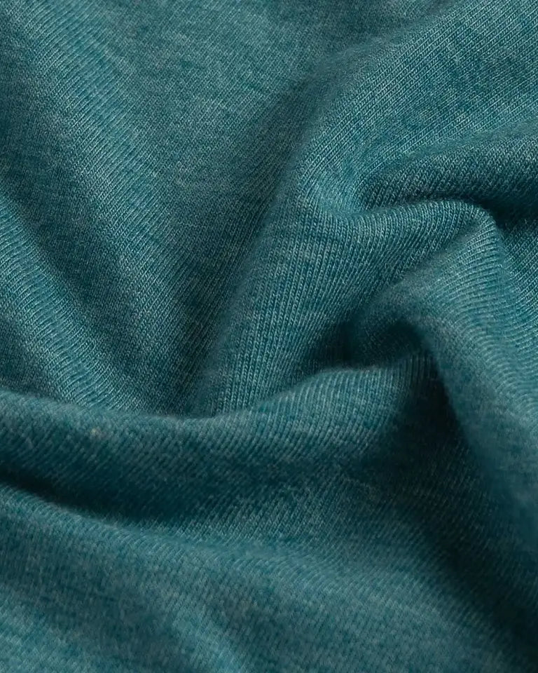 A close-up of draped teal blue fabric with a soft, slightly heathered texture.