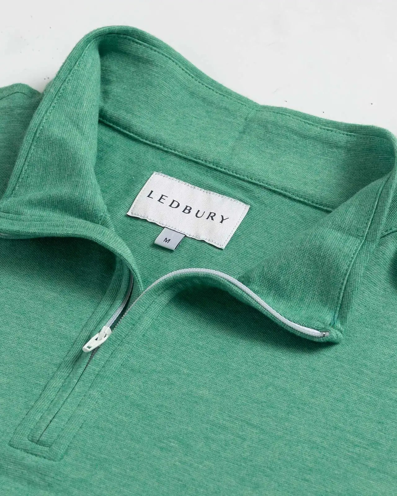Close-up of quarter-zip collar and Ledbury label on Freeman Sport Quarter Zip in Parakeet Green