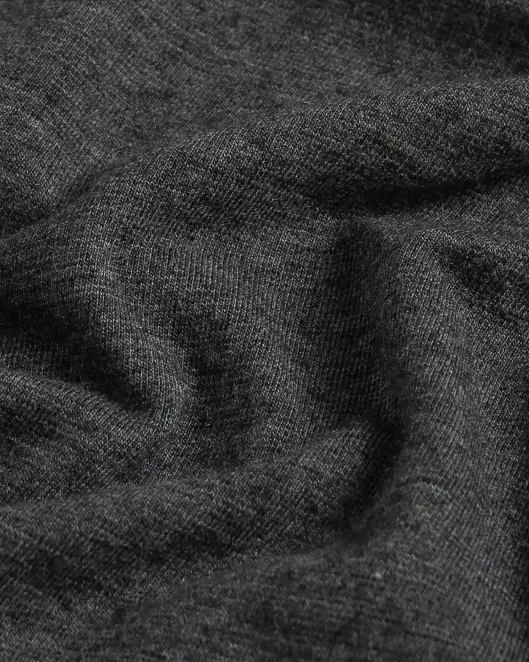 A close-up of dark charcoal gray knit fabric with soft folds and a fine ribbed texture.
