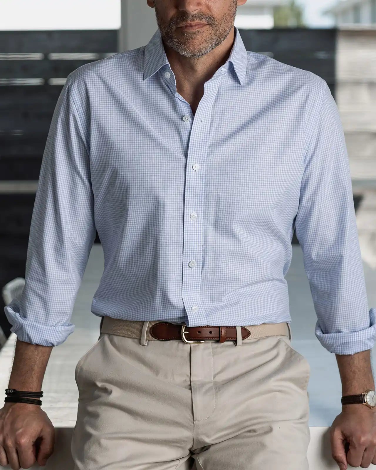 Man wearing a light blue checkered shirt and beige pants in an indoor setting