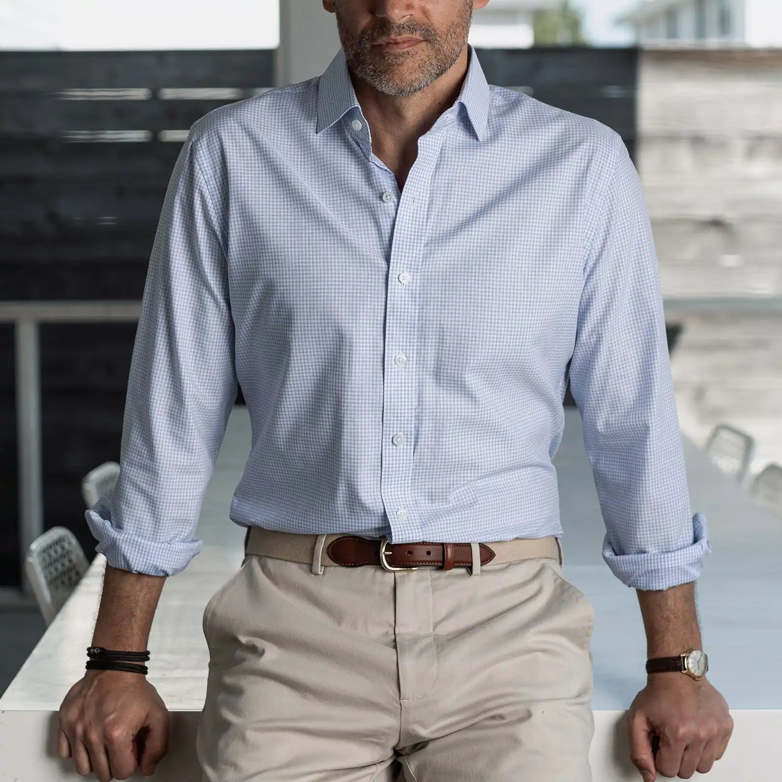 Man wearing a light blue checkered shirt and beige pants in an indoor setting