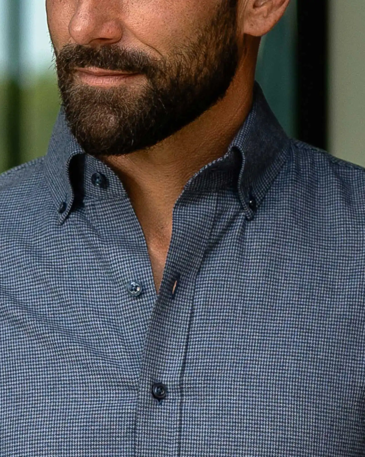 Close-up of a man wearing a blue micro-check patterned button-down shirt.