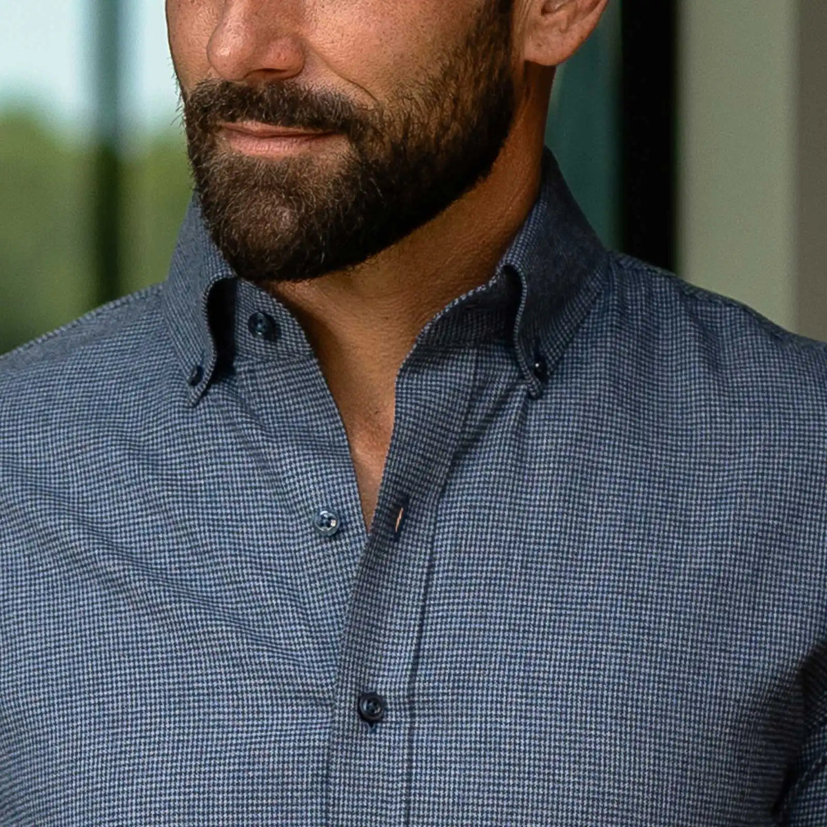 Close-up of a man wearing a blue micro-check patterned button-down shirt.