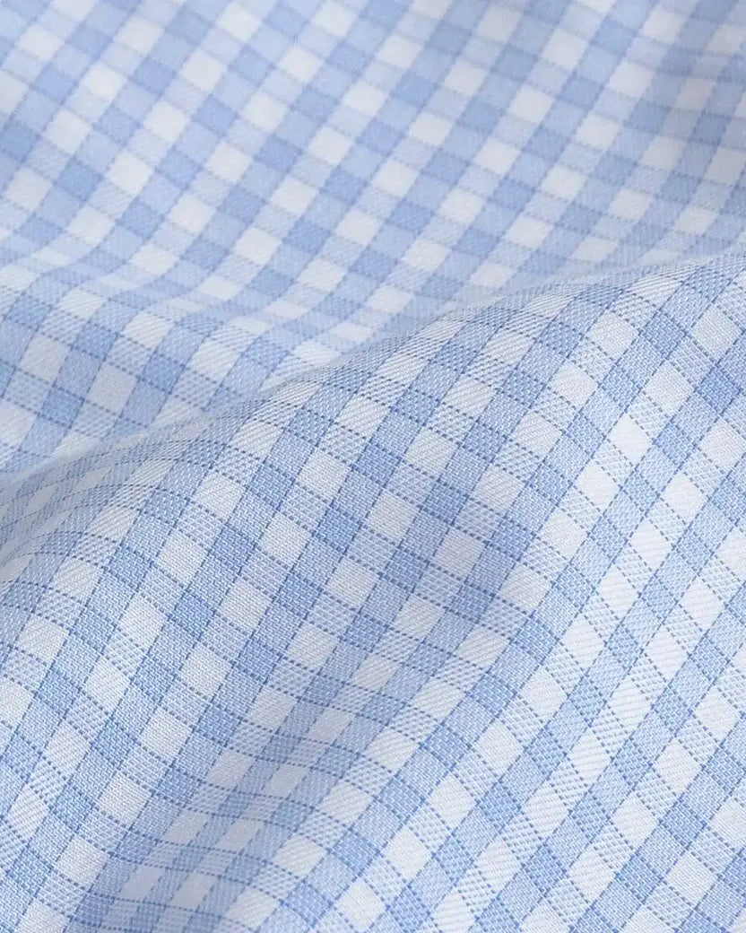 A close-up of light blue and white gingham fabric with a soft, draped fold showing the woven texture.