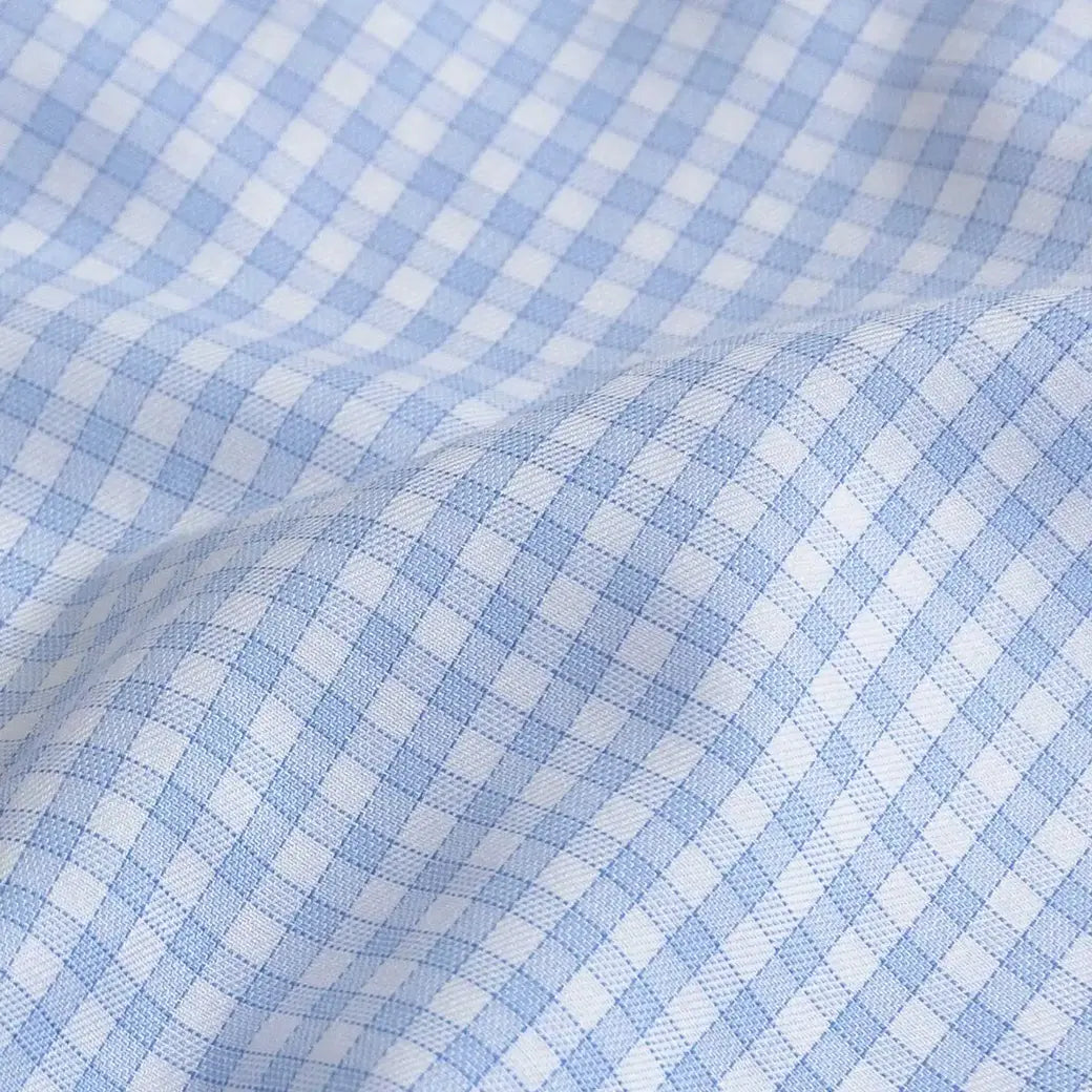 A close-up of light blue and white gingham fabric with a soft, draped fold showing the woven texture.