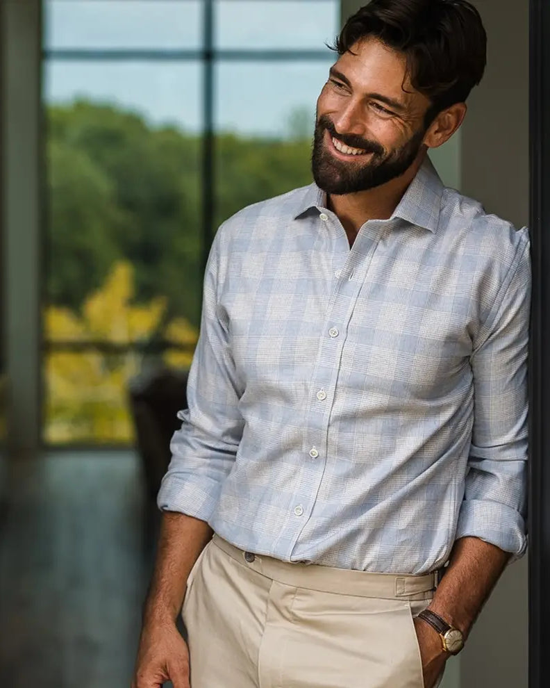 Man wearing a light blue and light grey business casual flannel shirt, standing in a doorway.