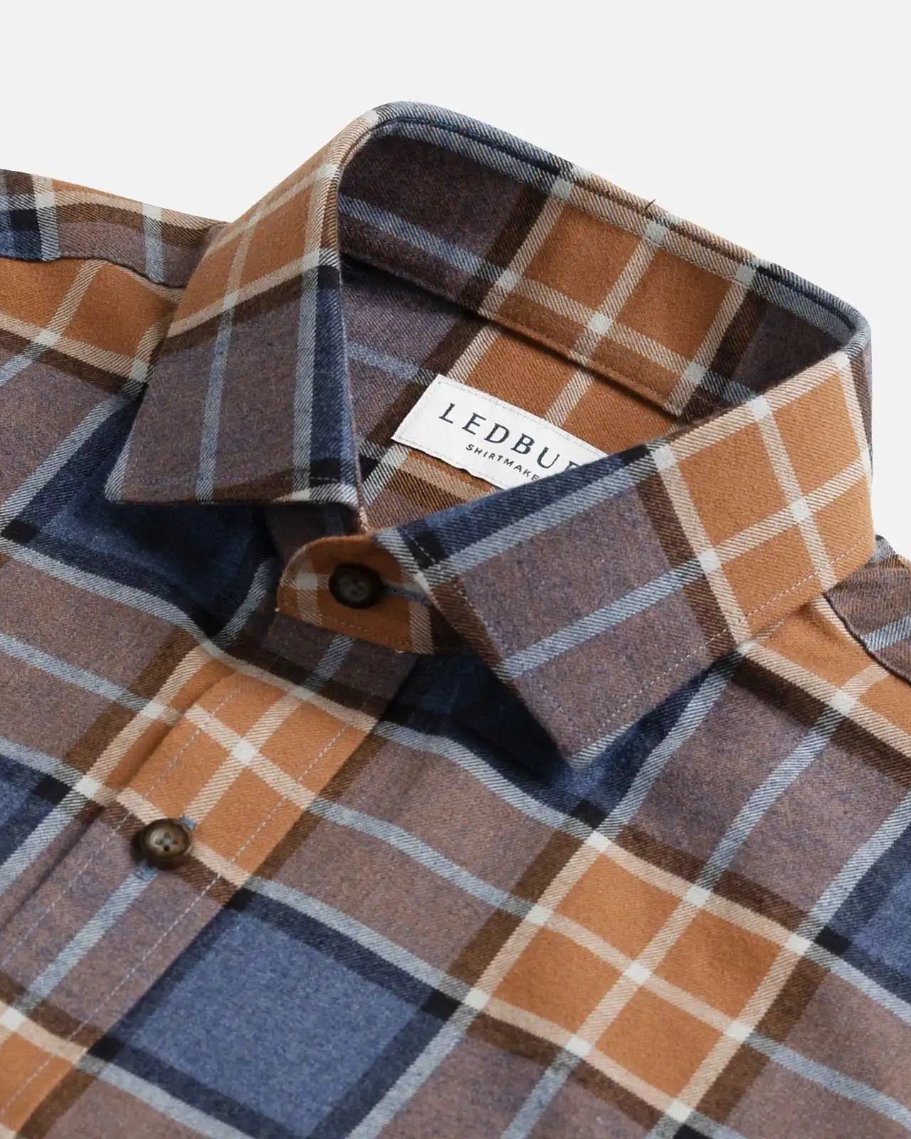 Burnt orange and blue plaid flannel shirt collar and button detail