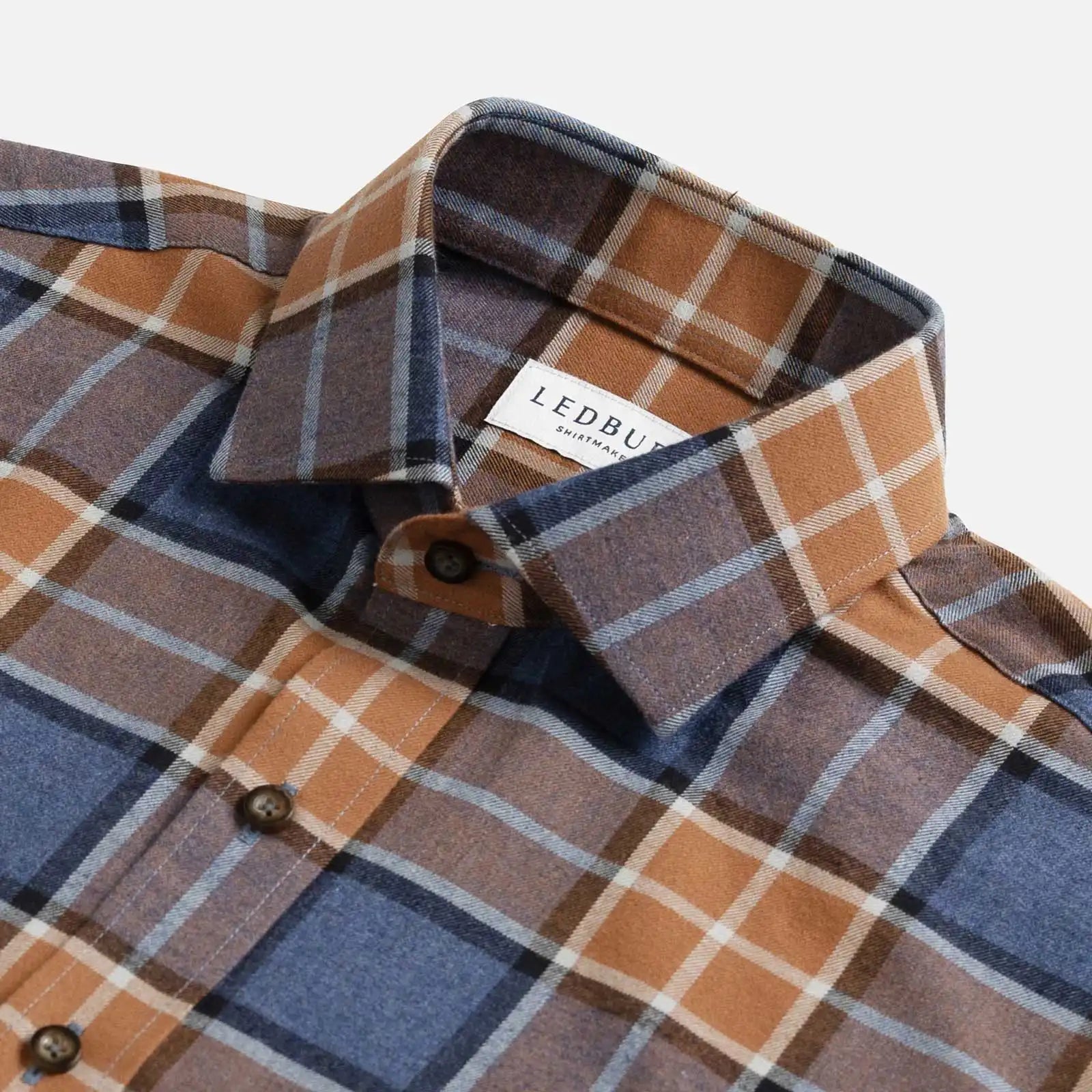 Burnt orange and blue plaid flannel shirt collar and button detail