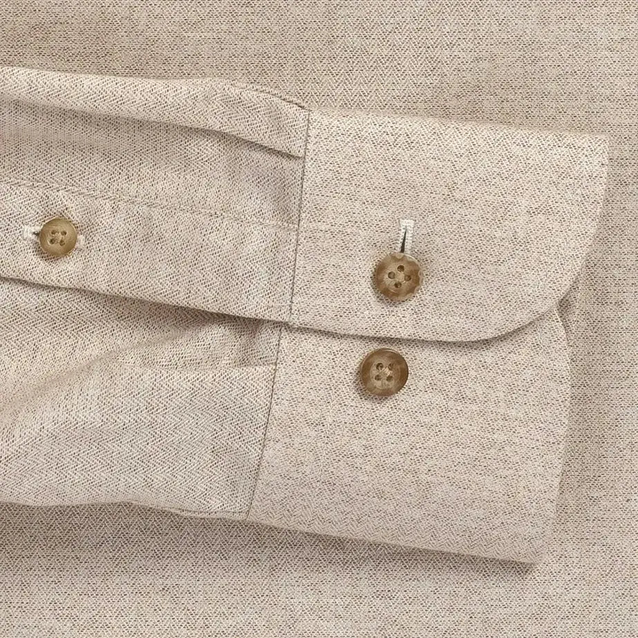 Close-up of a beige textured herringbone shirt with buttons