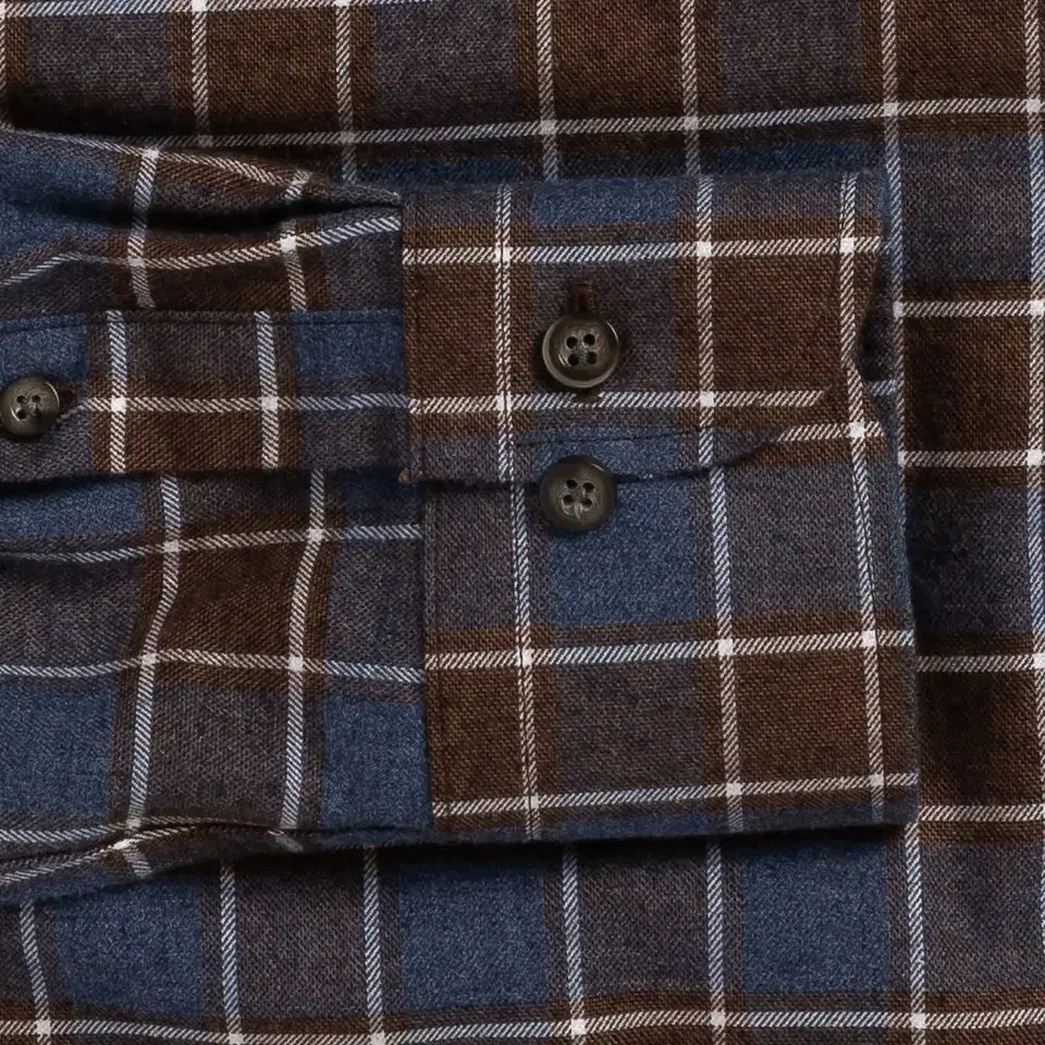 Close-up of a plaid buttoned cuff on a blue and brown flannel-style shirt, showing the fabric texture and dark buttons.