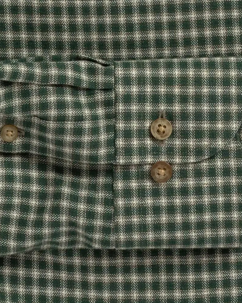 Close-up of a green and white gingham plaid shirt cuff with two brown buttons.