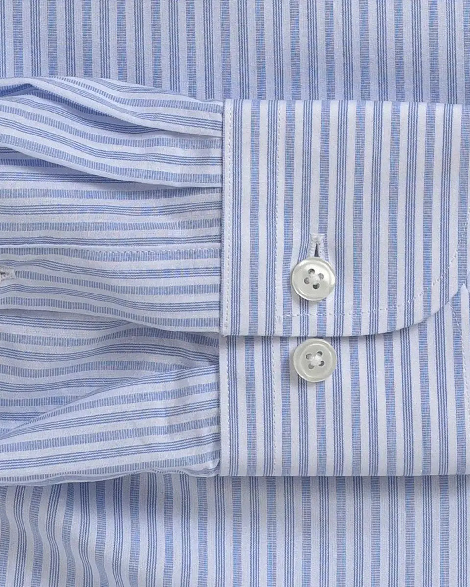 Close-up of a light blue and white striped dress shirt cuff with two white buttons, laid flat against the matching striped fabric.