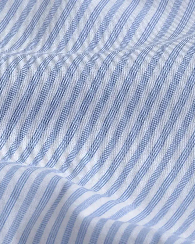 A close-up of a blue and white striped fabric with a fine textured weave and soft folds.