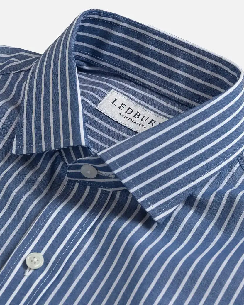 Close-up of a LEDBURY men's dress shirt with a blue and white vertical stripe pattern, featuring a classic collar and white buttons.