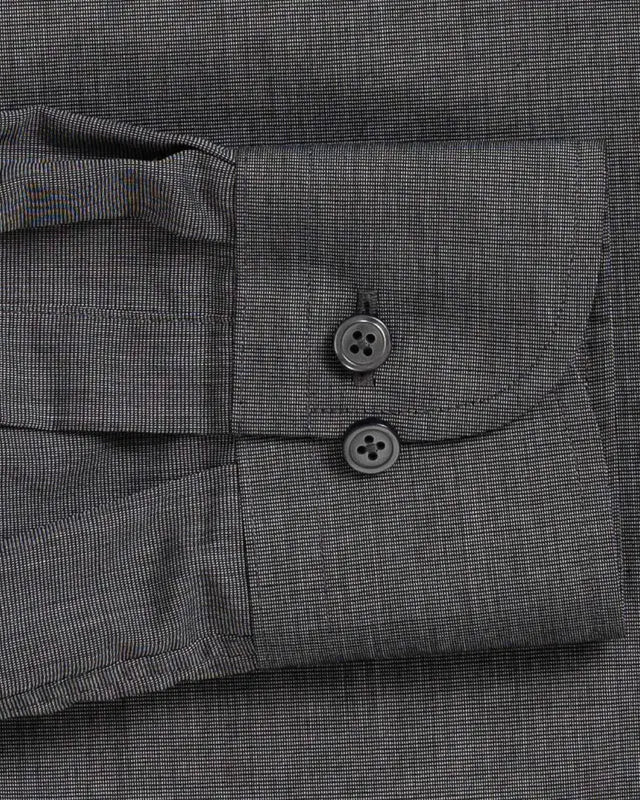 Close-up of a dark gray textured fabric shirt cuff with two dark buttons and a buttoned pocket flap.