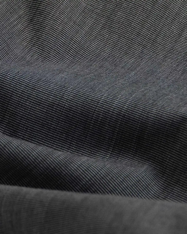 A close-up of dark charcoal gray fabric with a fine diagonal twill weave and soft folds.