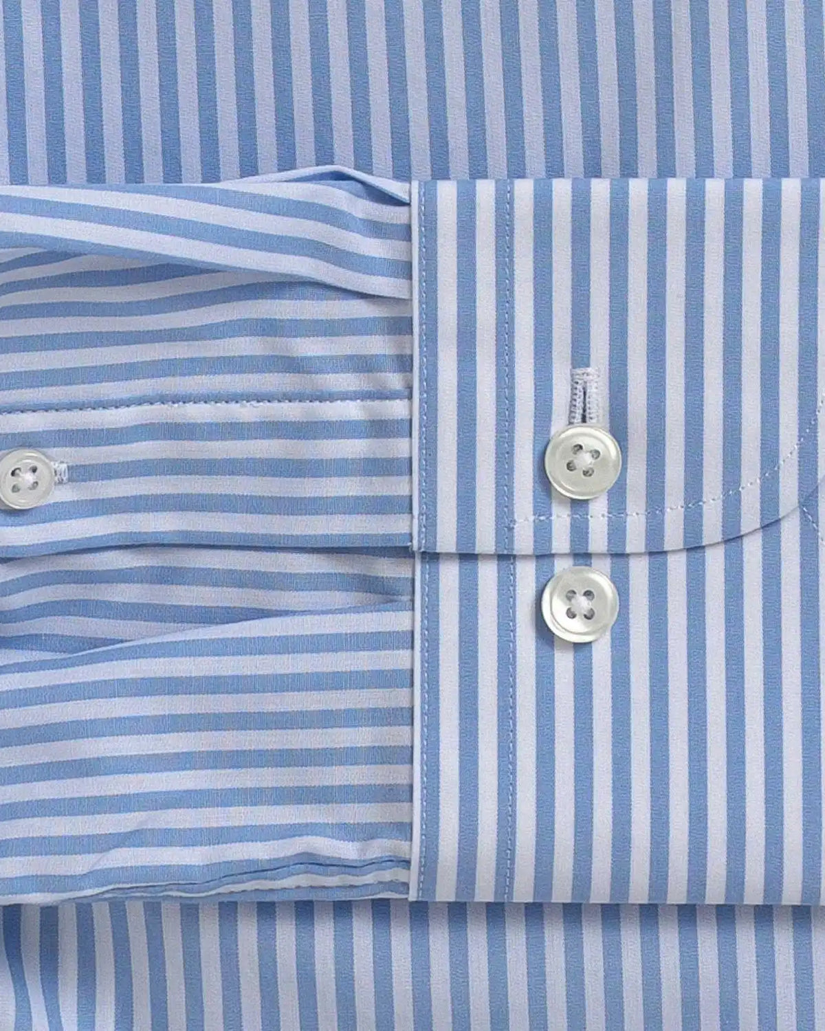 Close-up of a light blue and white striped dress shirt showing the buttoned cuff and front placket.