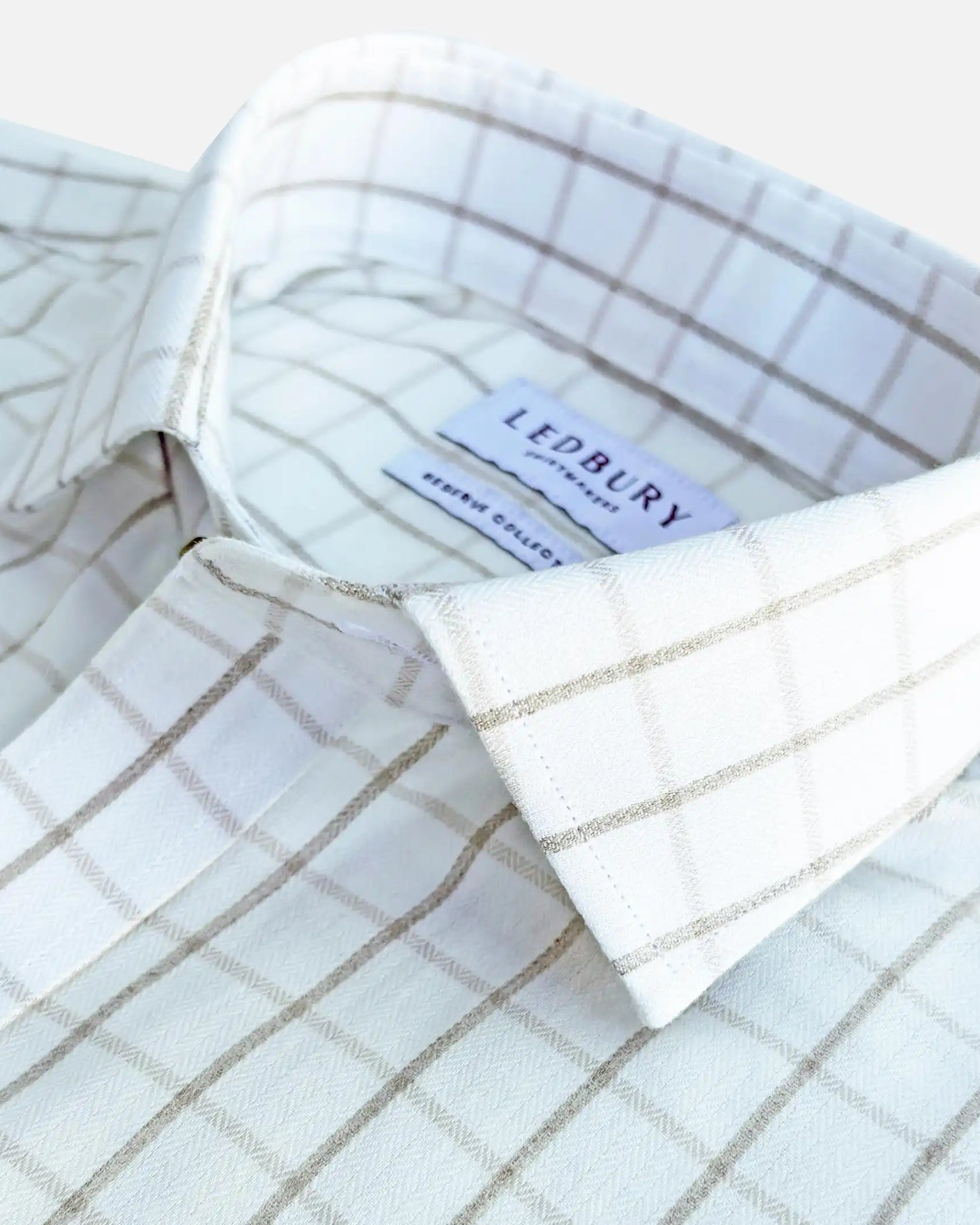 Close-up of a white and beige windowpane plaid dress shirt by Ledbury, showing the collar