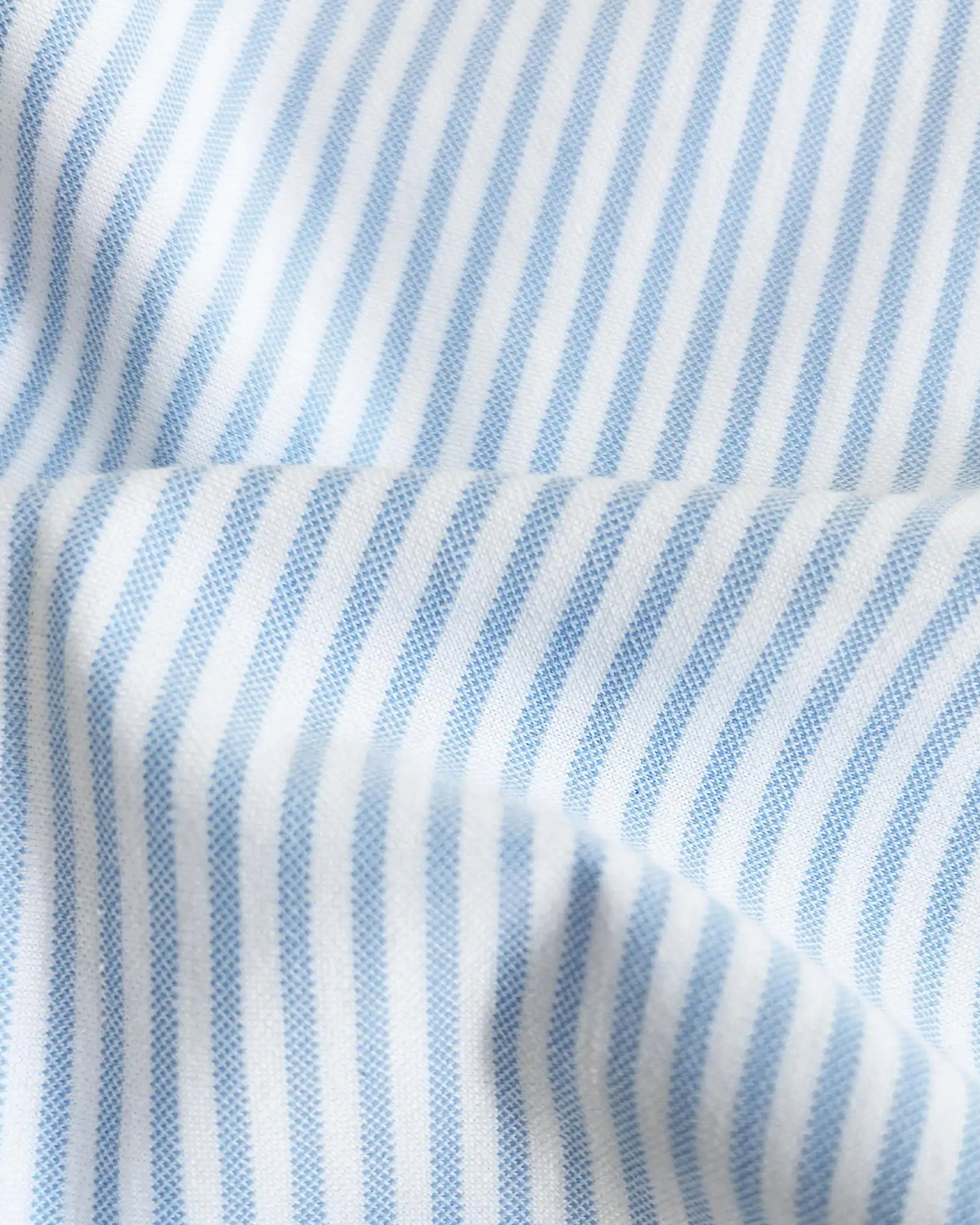 A close-up of light blue and white vertically striped fabric with a soft draped fold.