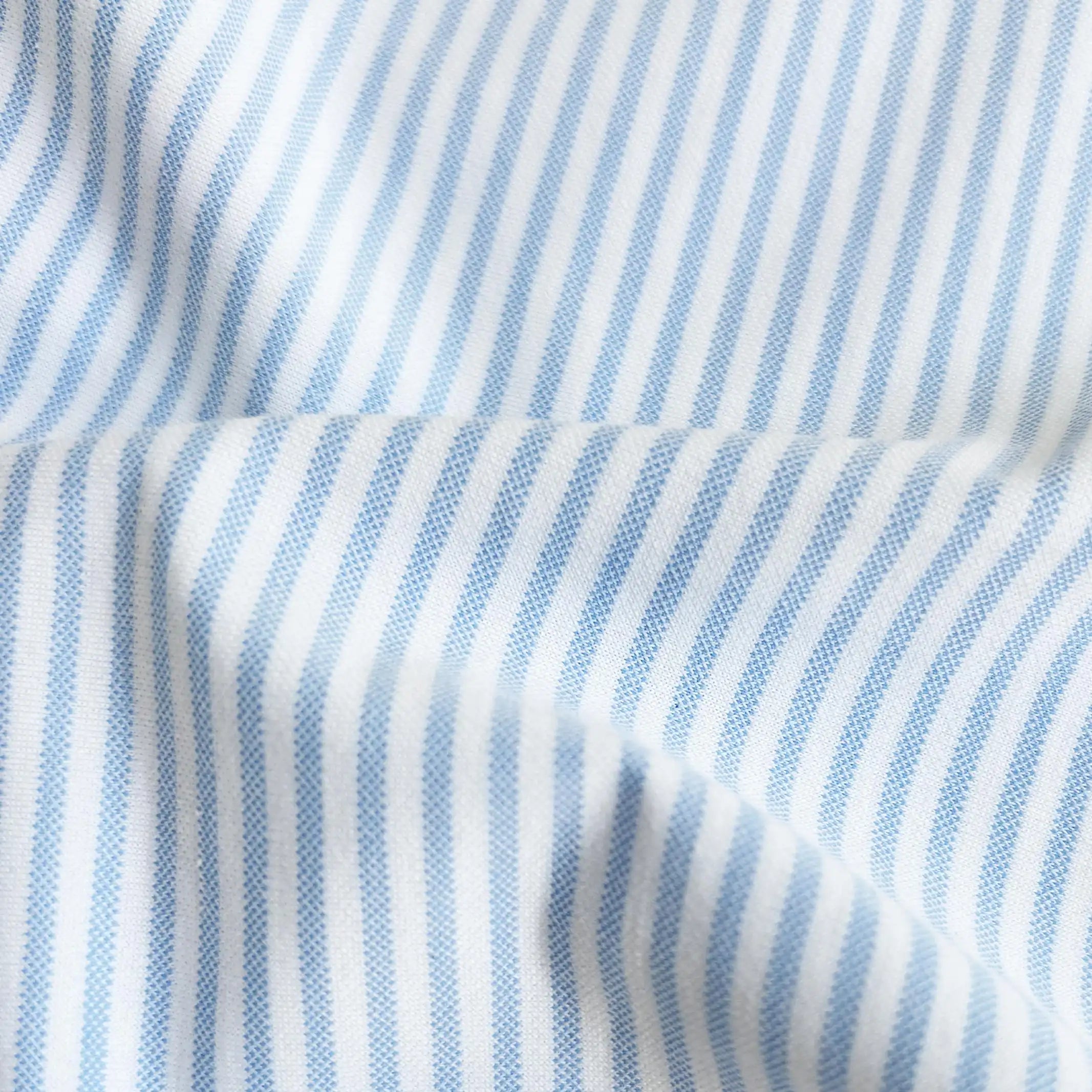 A close-up of light blue and white vertically striped fabric with a soft draped fold.