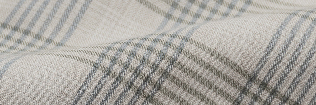 Closeup of the fabric of a men's tan, olive green and blue plaid button down shirt