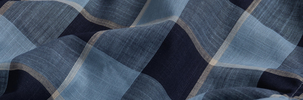 Closeup of the fabric of a men's Italian woven blue and navy check button down shirt