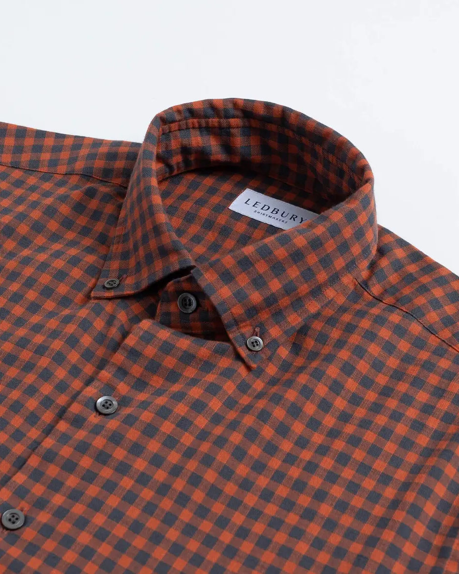 Close-up of a checkered button-down shirt collar in orange and dark gray, with a visible LEDBURY neck label.