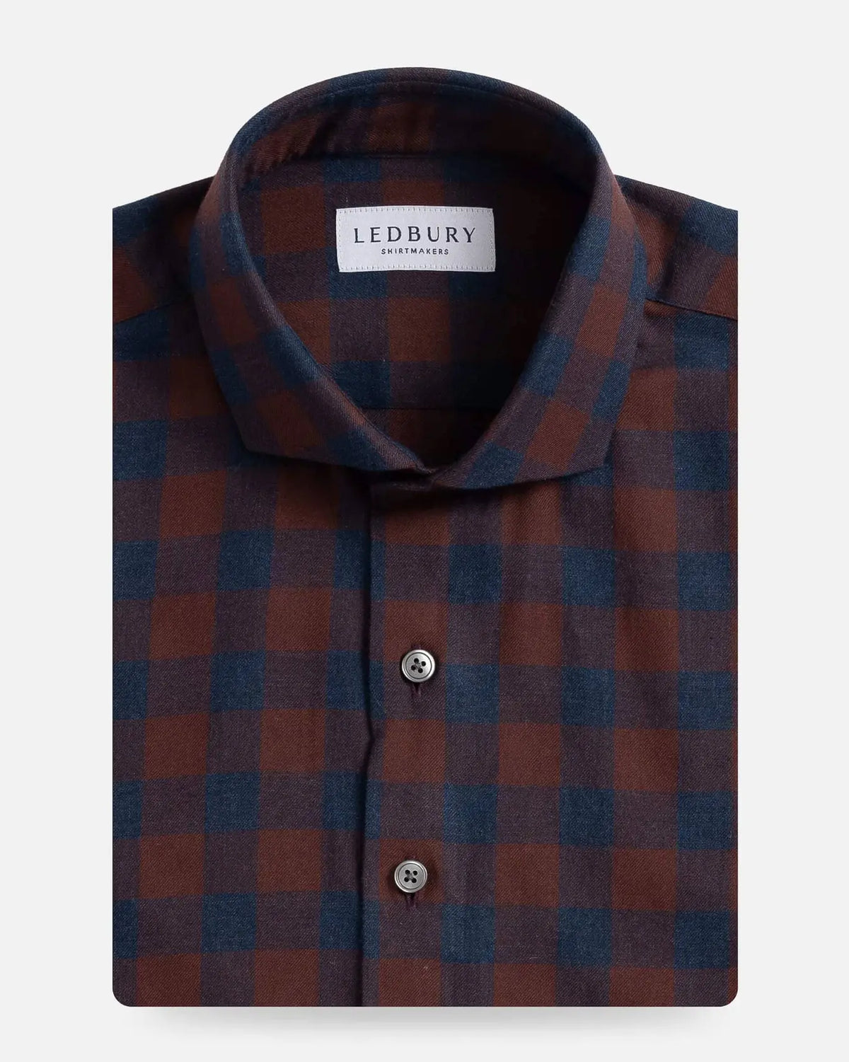 A folded men's dress shirt by Ledbury, featuring a classic checkered pattern in bordeaux red and navy blue. The shirt is neatly folded to show the collar, front button placket, and fabric texture against a clean, light gray background.