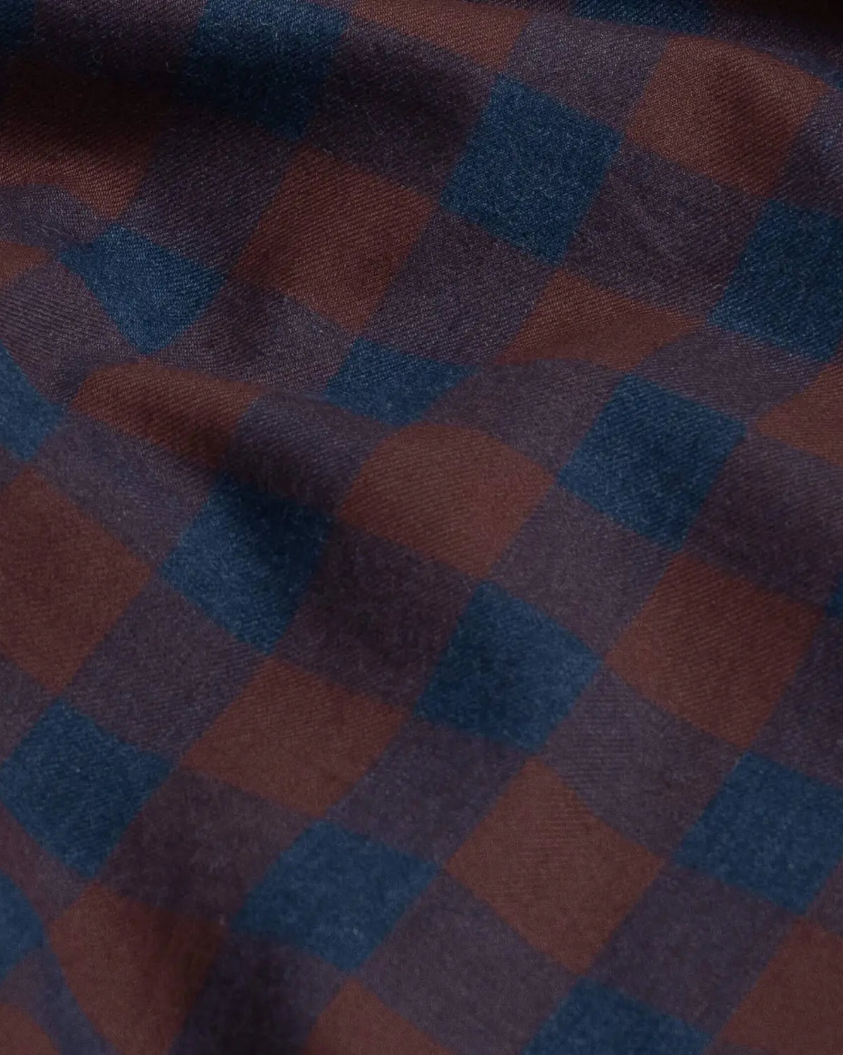 A close-up of a plaid fabric with a checkered pattern in dark blue and bordeaux red.