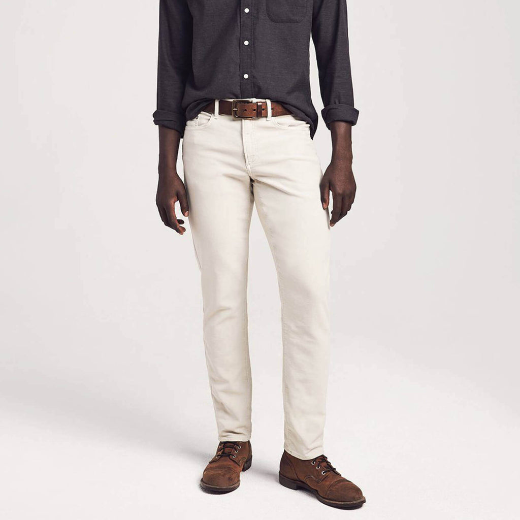 A male model wearing a pair of light khaki colored 5 pocket pants
