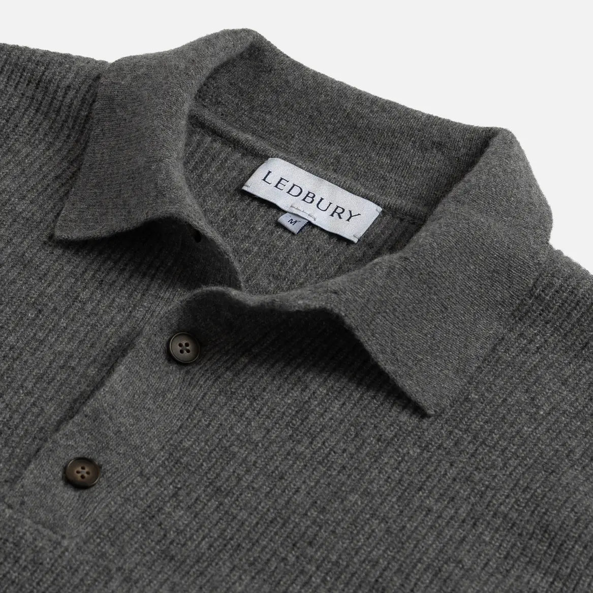 Close-up of a dark gray ribbed knit polo sweater collar with two buttons and a visible LEDBURY neck label.