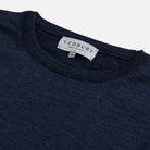Close-up of a navy blue knit crewneck sweater with a white LEDBURY neck label.