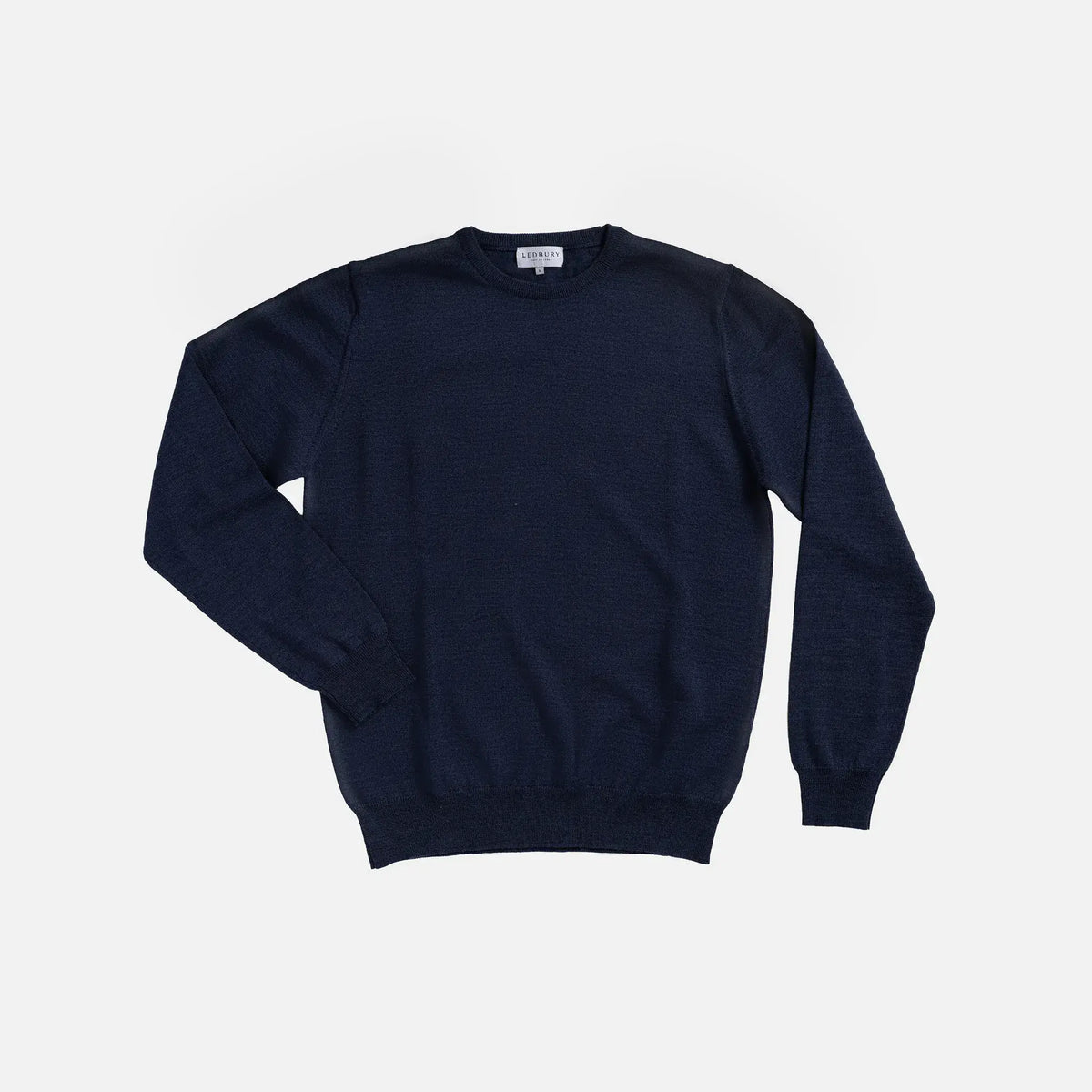 A dark navy blue crewneck sweater laid flat against a light gray background.
