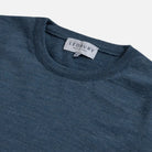 Close-up of a ribbed crewneck sweater in a heathered slate blue color, showing the interior neck label with the brand name LEDBURY.