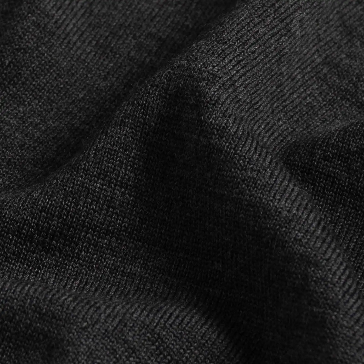 Close-up of a dark charcoal gray ribbed knit fabric texture with soft folds.