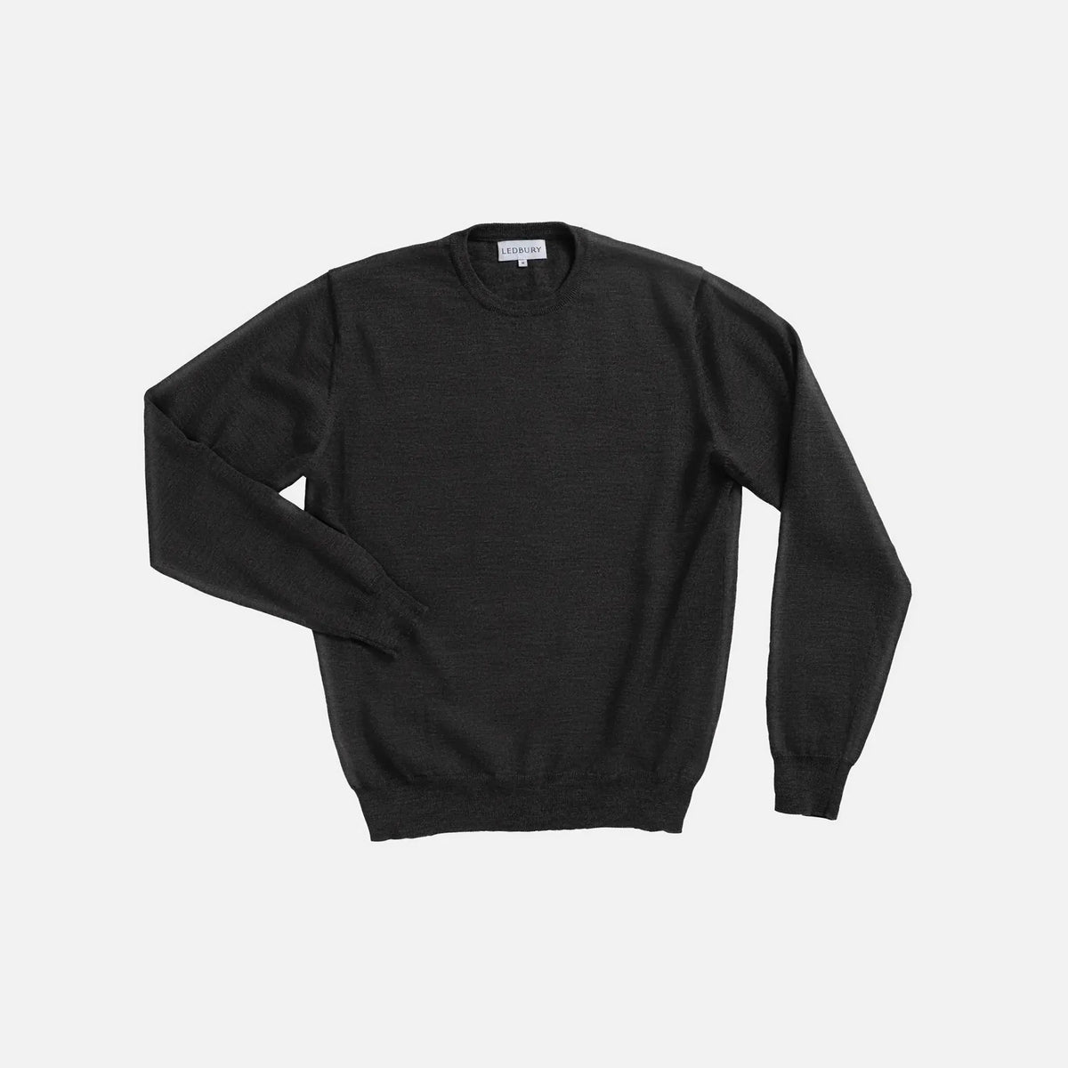 A dark charcoal gray crewneck sweater with long sleeves, laid flat against a light gray background.