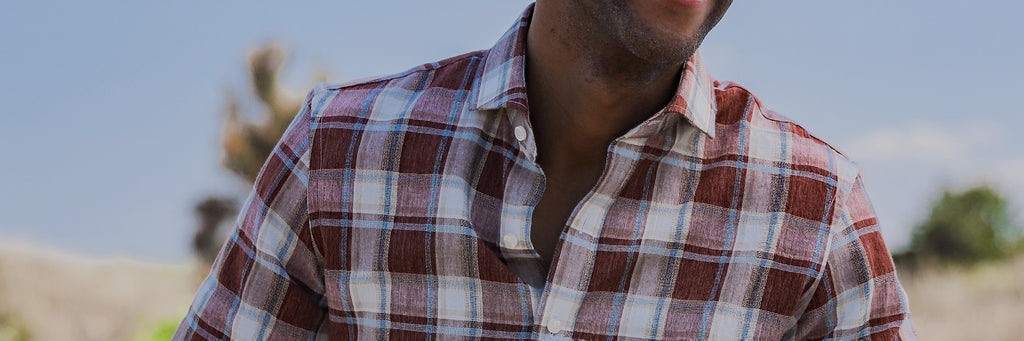 Male model wearing a brick red, blue and white button down shirt