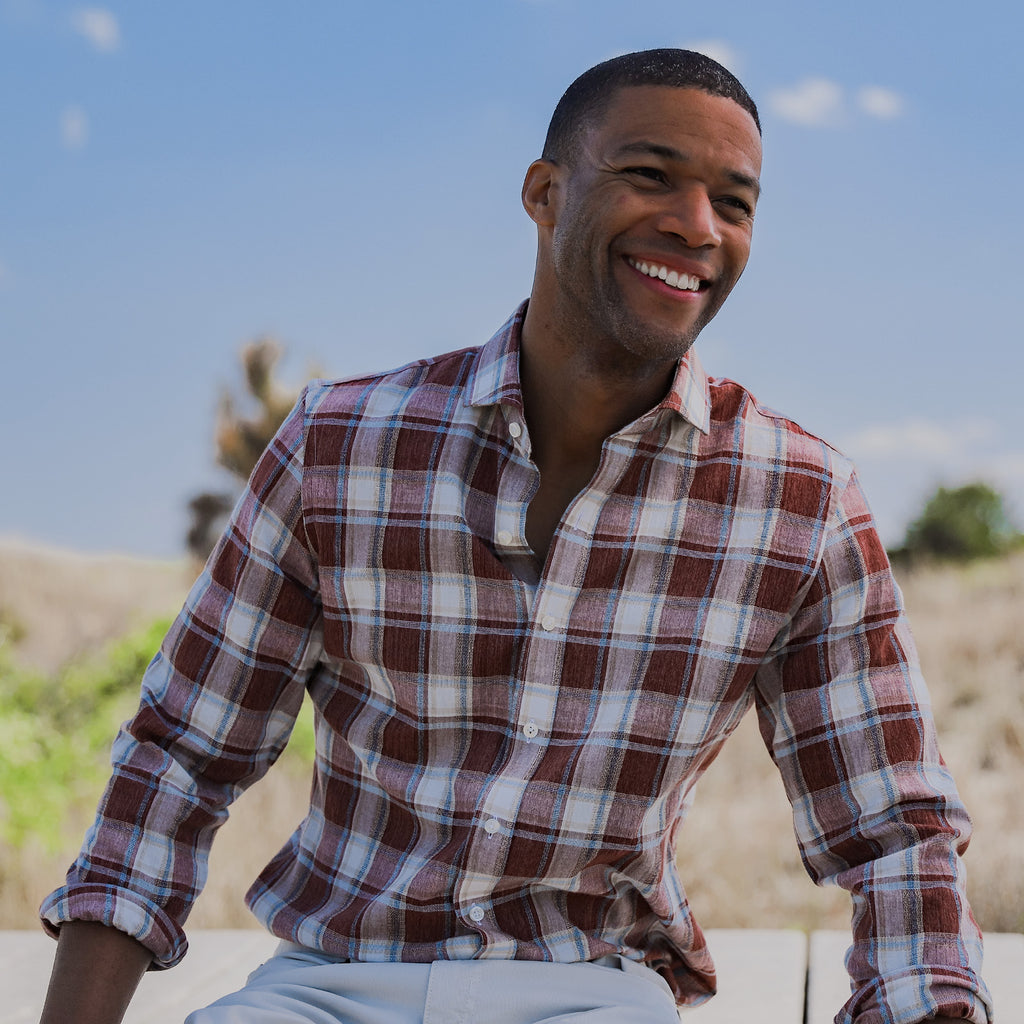 Male model wearing a brick red, blue and white button down shirt