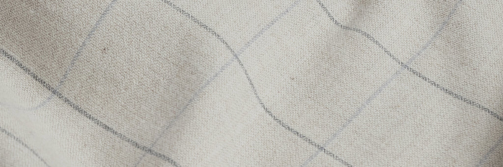 Closeup of the fabric of a men's cream colored button down flannel with a large scale grey check 