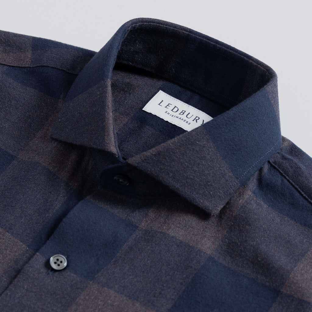 Closeup of the collar of a men's navy and grey checked flannel shirt
