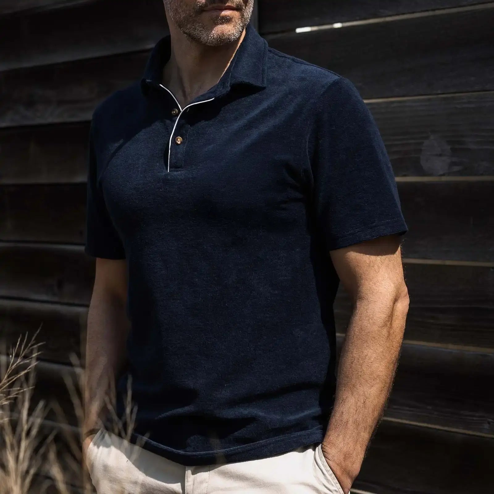 Man wearing a navy blue terry cloth polo shirt against a wooden background