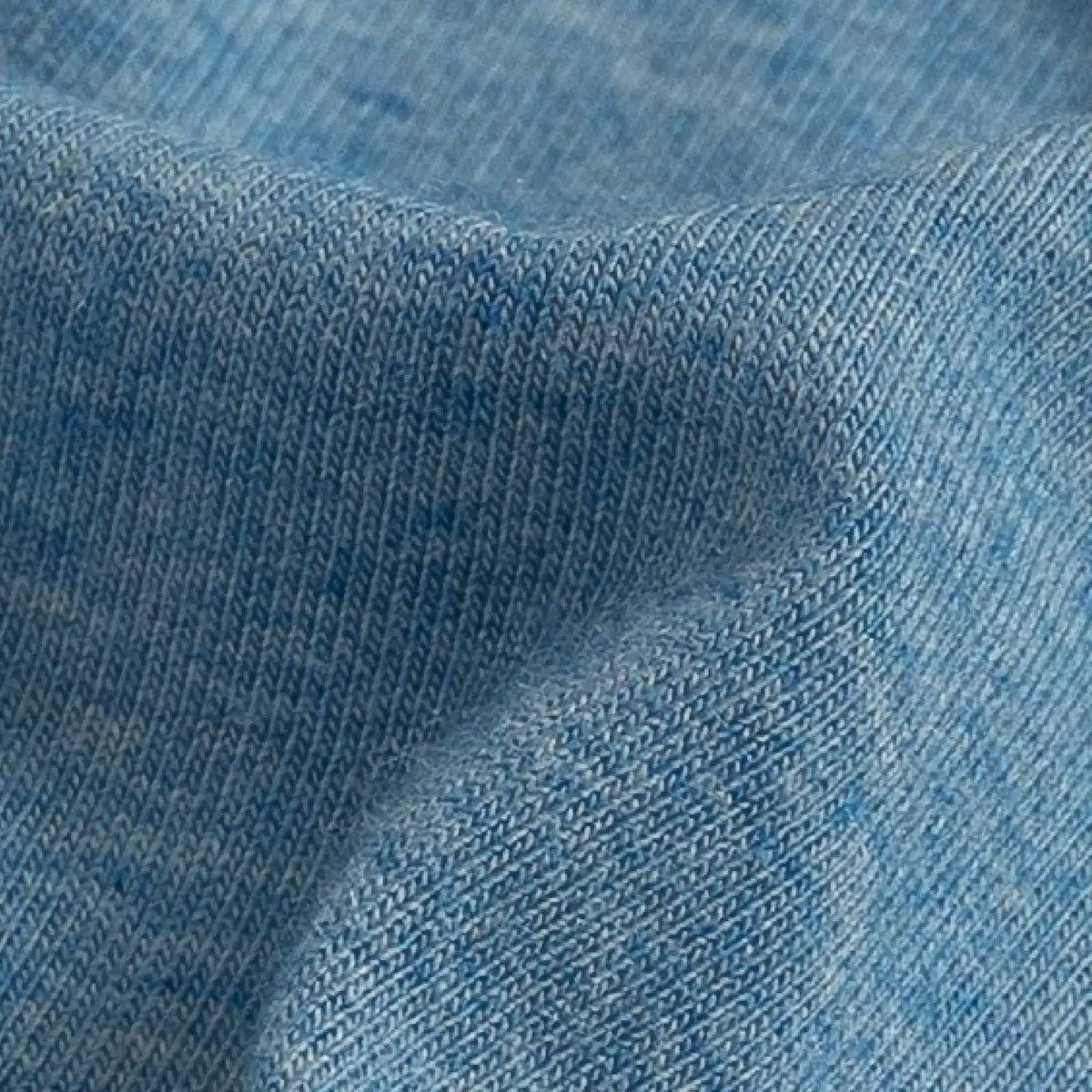 A close-up of light blue knit fabric with a fine ribbed texture and soft folds.