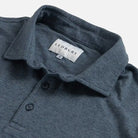 Close-up of a slate blue polo shirt collar with a visible LEDBURY neck label and two dark buttons on a light gray background.
